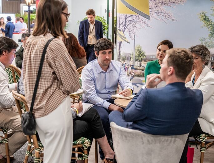 Discussion between professionals at SIEC 2025, with several participants seated around a table in a networking and meeting area.